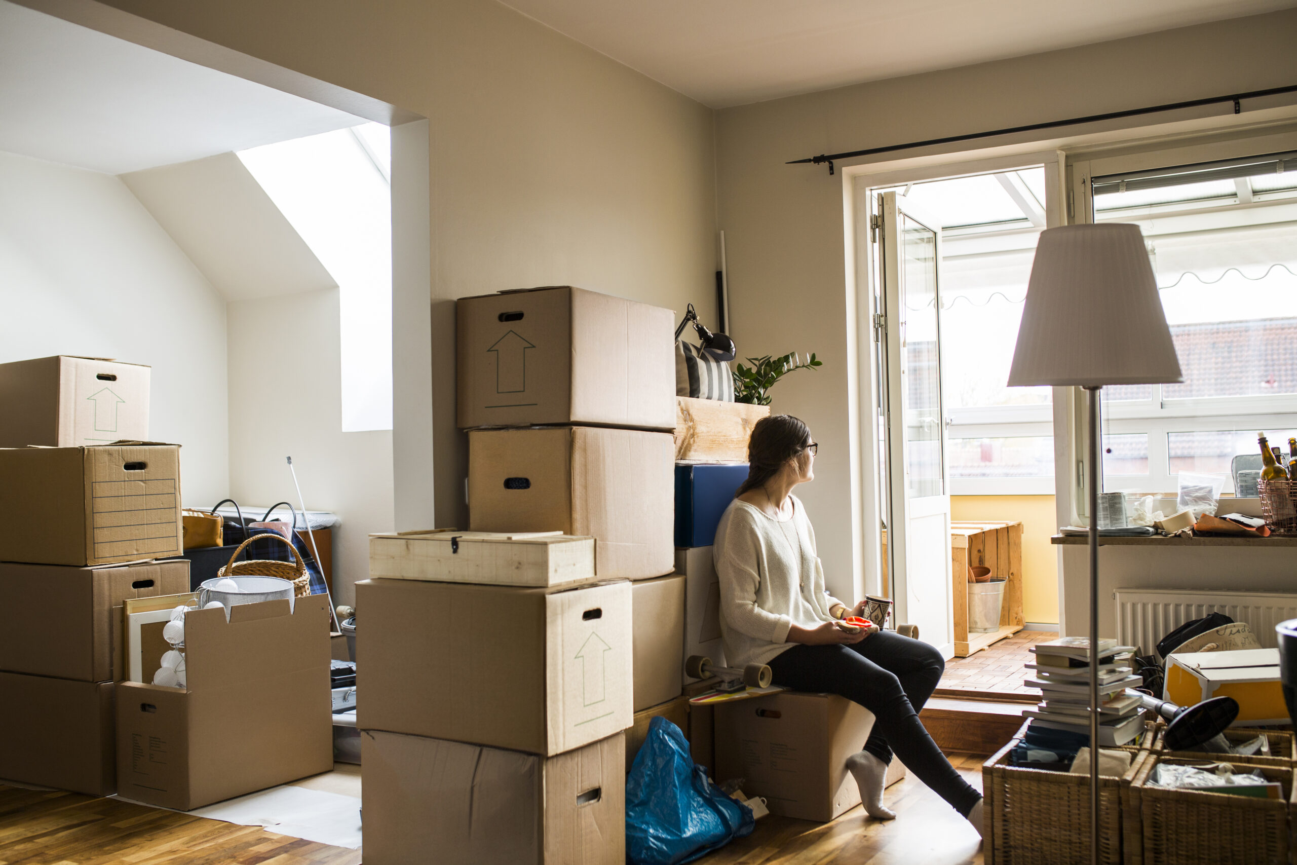 Person sitting among moving boxes in an inherited home