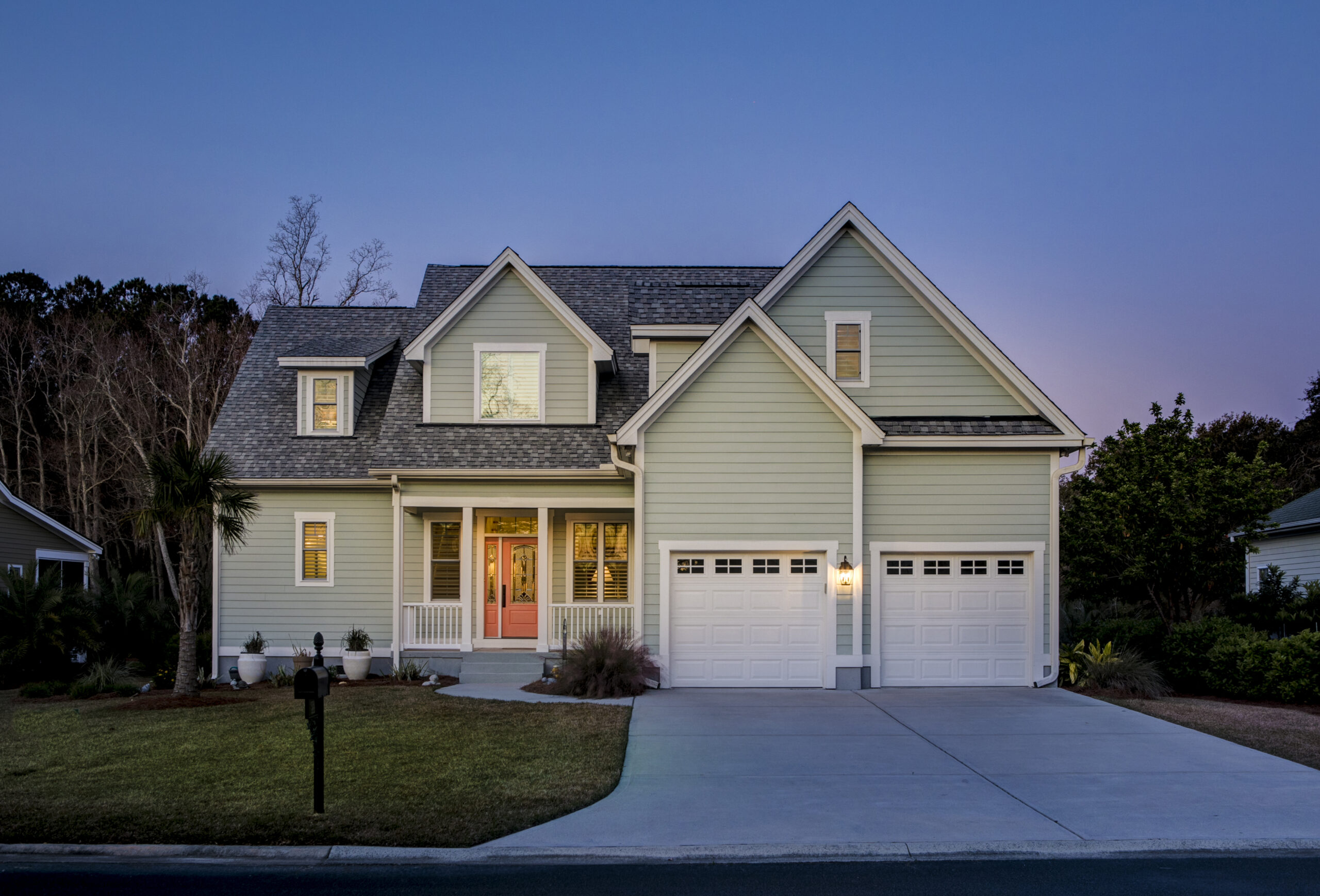 Suburban home with a paved driveway and attached garage at twilight.
